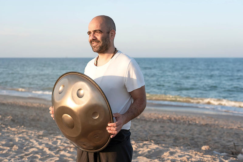 handpan acheter, instrument hang, homme tient un handpan sur la  plage